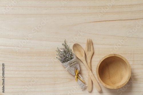 Wooden spoon and fork with wooden bowl on wooden background.