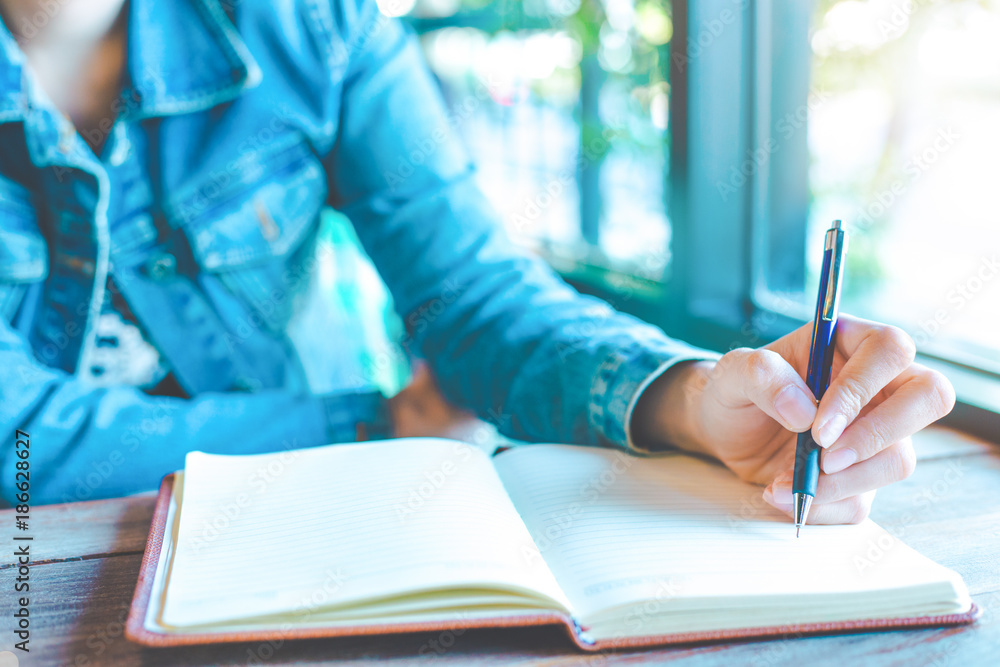 Woman hand is writing on a note pad with a pen in the office.