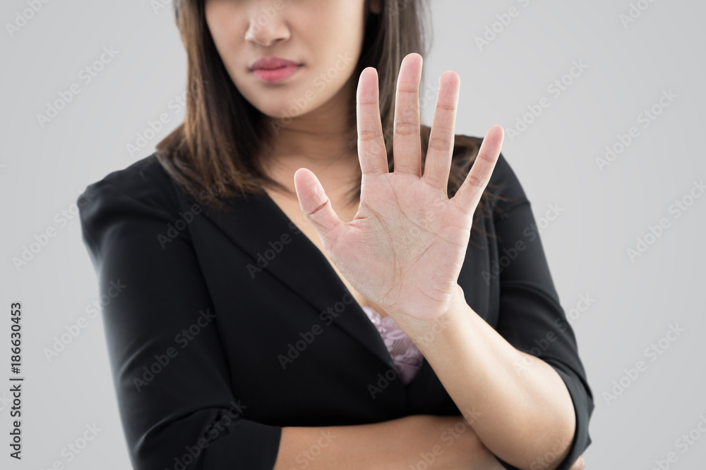 Business woman in black suit showing her denial with no on her hand against gray background Business woman in black suit showing her denial with no on her hand against gray background