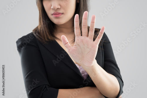 Business woman in black suit showing her denial with no on her hand against gray background