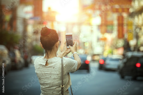 woman tourist taking a photograph with smart phone in yaowarat china town bangkok thailand