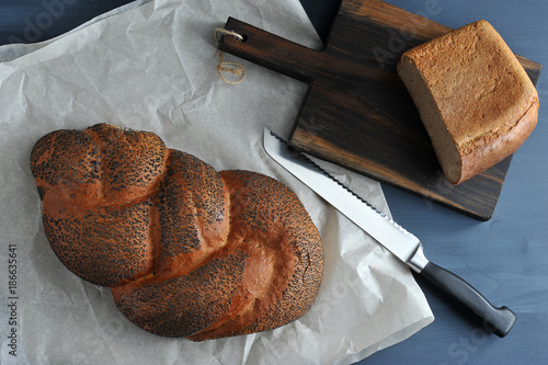 braided loaf with poppy seeds on brown paper with a knife for the bread and half of bread photo