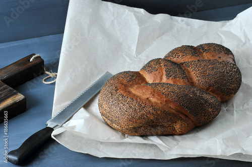 braided loaf with poppy seeds on brown paper with a bread knife