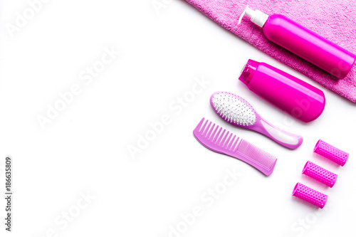 Basic hair care in bathroom. Comb  shampoo  spray  curlers  towel on white background top view copyspace