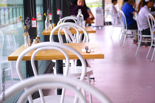 Photography Cafe interior with big windows, wooden tables and white chairs
