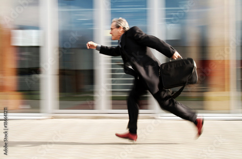 Running Businessman in front of generic modern office buildings with action and motion blur