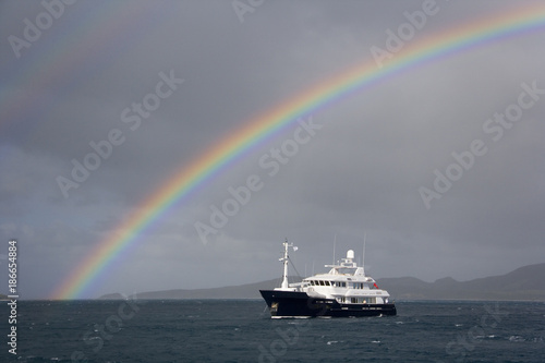 Luxury yacht under a rainbow off the coast of Fiji in the South Pacific