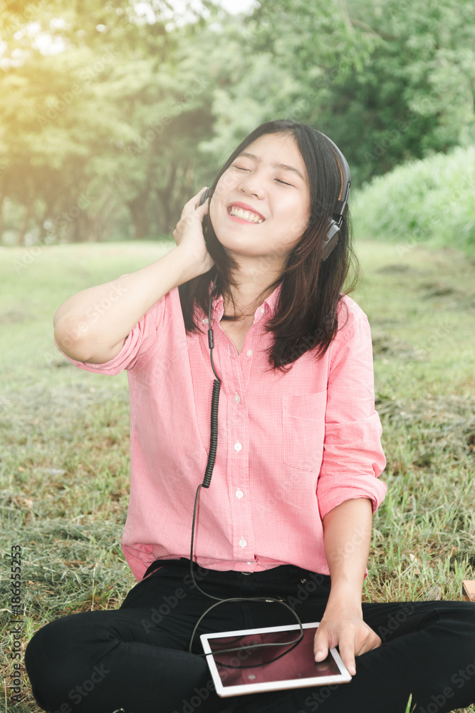 asian young girl happy learning song on tablet and headphones in natural