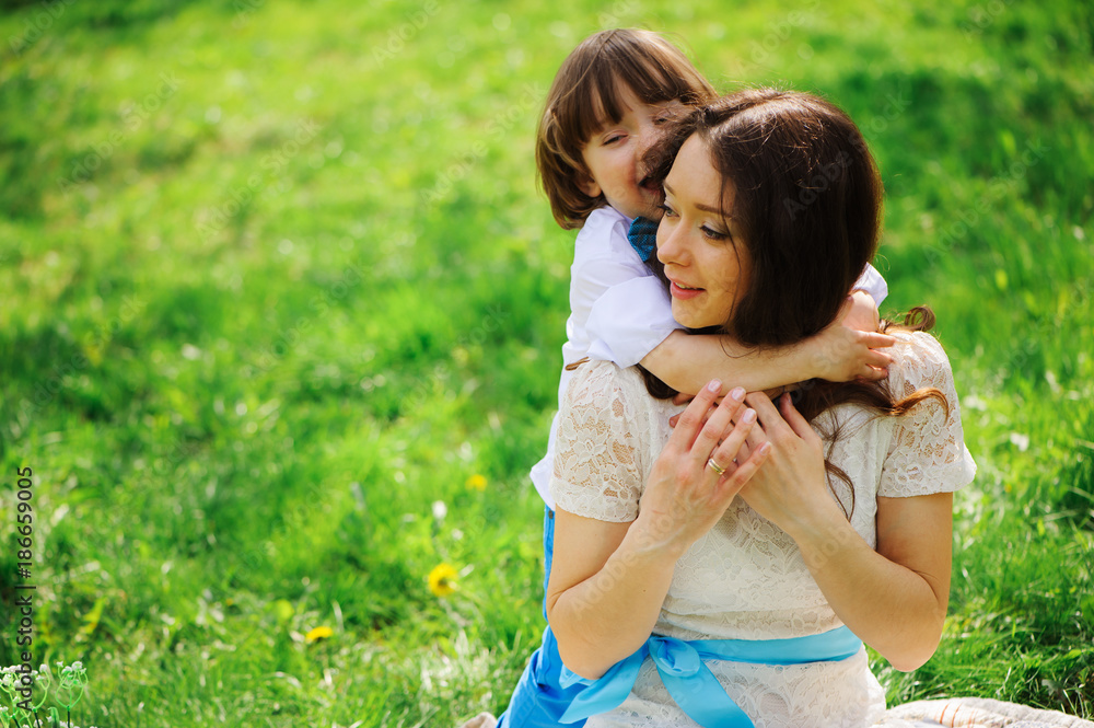happy mom hugs and kiss toddler kid son outdoor in spring or summer. Loving family and mothers day concept. happy mom hugs and kiss toddler kid son outdoor in spring or summer. Loving family and mothers day concept.