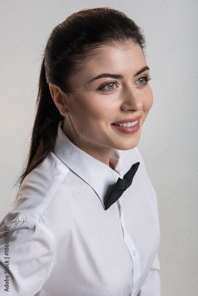 Inspiration coming. Adorable jolly merry woman looking straight and  wearing shirt while smiling  on the grey background