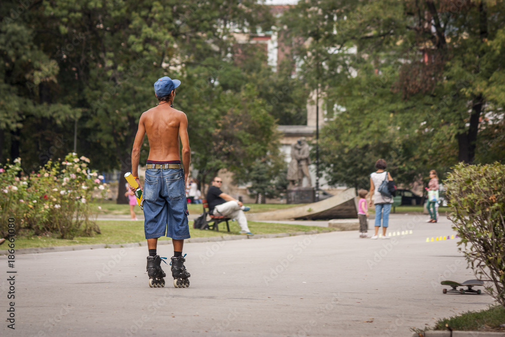 Obraz premium young man is doing roller skates in the park in the city naked to the waist. the sport for one in a peaceful world.