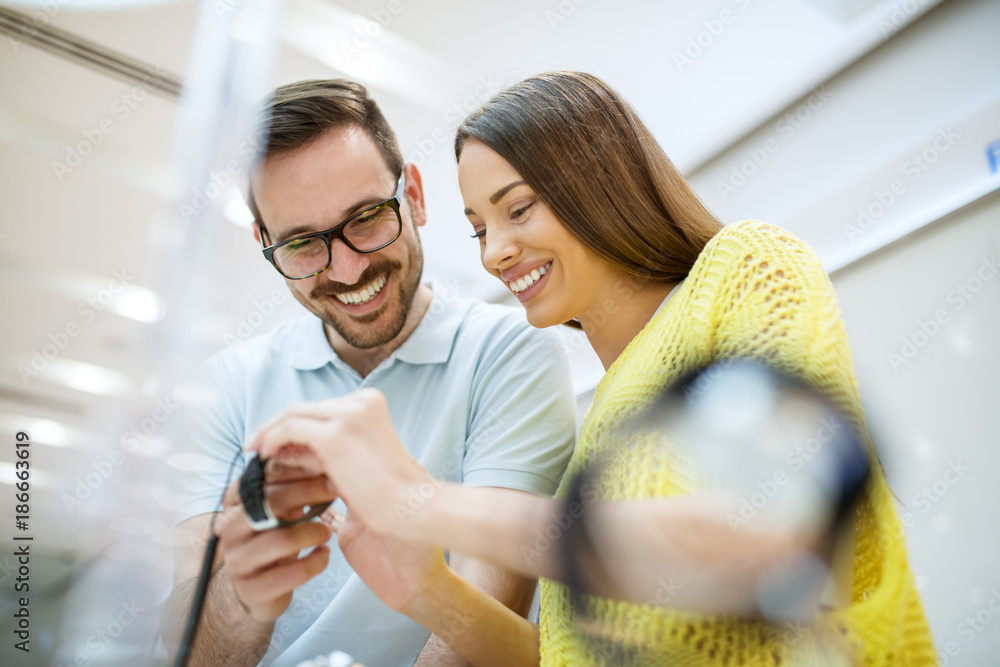 Portrait of happy satisfied smiling young couple in love holding a wristwatch in a tech store. Portrait of happy satisfied smiling young couple in love holding a wristwatch in a tech store.