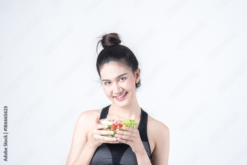 Fitness and health concept. Portrait of fit sport woman holding green salad bowl, isolated on white background. Chinese woman with black tank top and pants. Fitness and health concept. Portrait of fit sport woman holding green salad bowl, isolated on white background. Chinese woman with black tank top and pants.