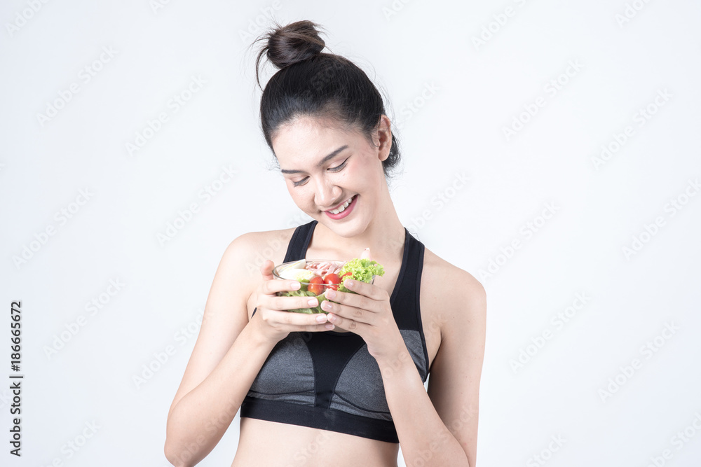 Fitness and health concept. Portrait of fit sport woman holding green salad bowl, isolated on white background. Chinese woman with black tank top and pants. Fitness and health concept. Portrait of fit sport woman holding green salad bowl, isolated on white background. Chinese woman with black tank top and pants.