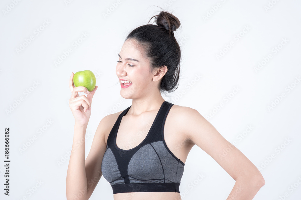 Fitness and health concept. Portrait of fit sport woman holding green apple, isolated on white background. Chinese woman with black tank top and pants. Fitness and health concept. Portrait of fit sport woman holding green apple, isolated on white background. Chinese woman with black tank top and pants.