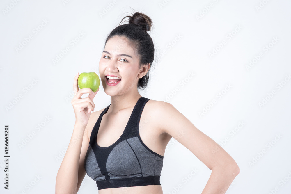 Fitness and health concept. Portrait of fit sport woman holding green apple, isolated on white background. Chinese woman with black tank top and pants. Fitness and health concept. Portrait of fit sport woman holding green apple, isolated on white background. Chinese woman with black tank top and pants.