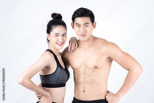 Fitness and health concept. Portrait of fit sport man and woman looking confidence, isolated on white background. Half naked Asian chinese lean muscular male wearing a black shorts with chinese woman.