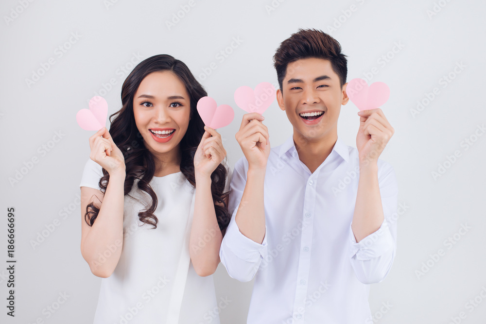 Happy young Vietnamese couple is holding pink paper hearts and smiling Happy young Vietnamese couple is holding pink paper hearts and smiling