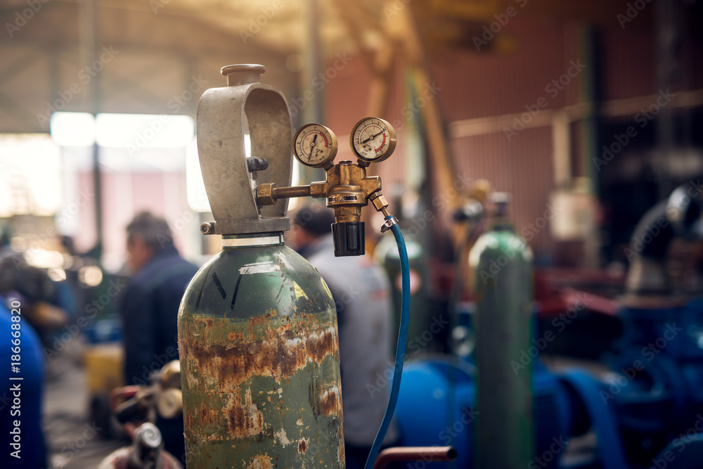 Close up focus view of welding equipment. Acetylene gas cylinder tank with gauge regulators manometers in the industrial fabric workshop.
