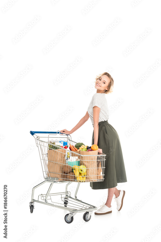 cheerful young woman standing with shopping trolley and smiling at camera isolated on white cheerful young woman standing with shopping trolley and smiling at camera isolated on white