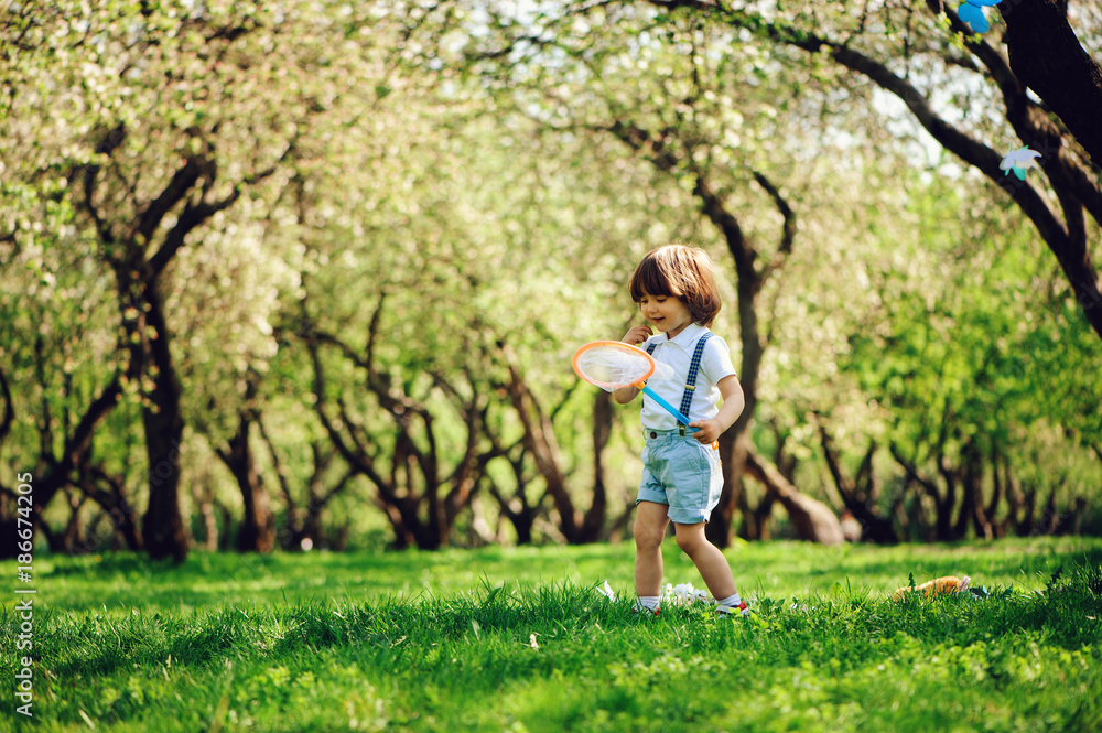 happy 3 years old child boy catching butterflies with net on the walk in sunny garden or park. Spring and summer outdoor activities, happy childhood concept. happy 3 years old child boy catching butterflies with net on the walk in sunny garden or park. Spring and summer outdoor activities, happy childhood concept.