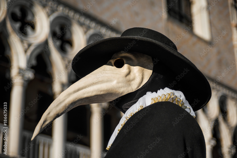 Fototapeta premium Plague Doctor Mask, tradycyjny wenecki kostium karnawału weneckiego, z gotycką dekoracją w tle Pałacu Dożów