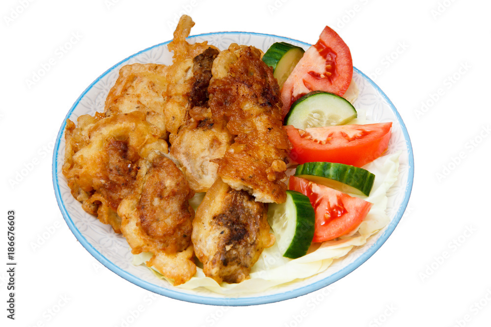 Plate with pieces of fried fish and freshly sliced tomatoes and cucumbers on isolated background Plate with pieces of fried fish and freshly sliced tomatoes and cucumbers on isolated background