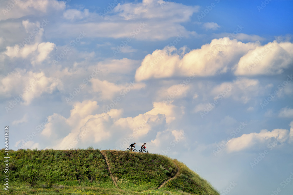 Two mountain bikers on the hill in Khodosivka, Kyiv, Ukraine, 25.06.2017 Two mountain bikers on the hill in Khodosivka, Kyiv, Ukraine, 25.06.2017