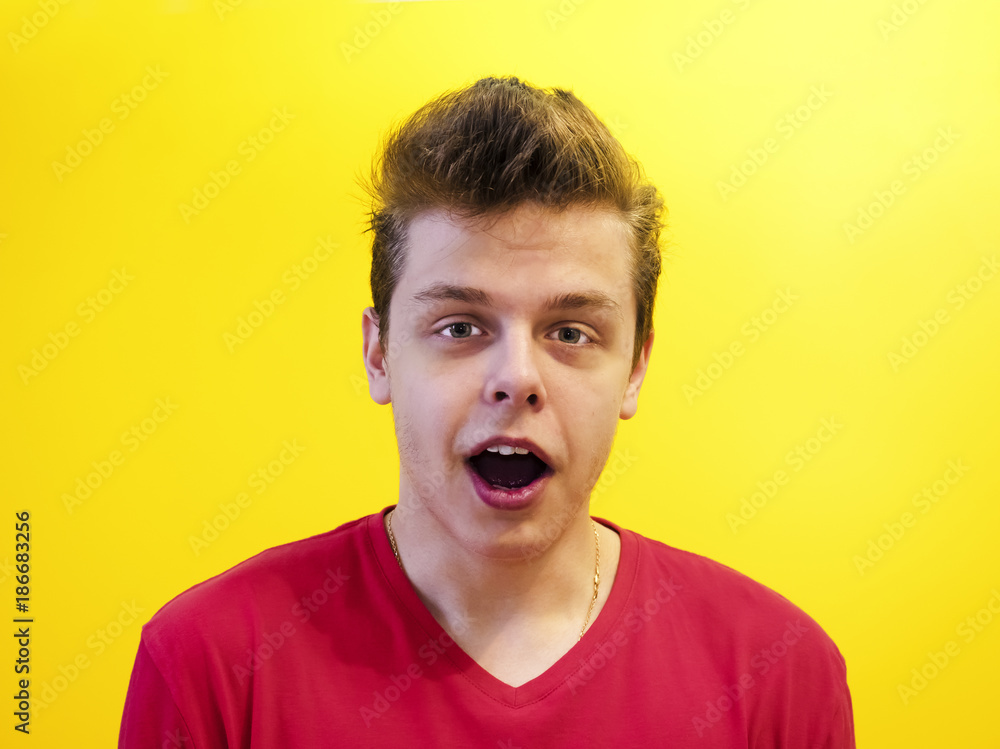Portrait of a young man with a shocked facial expression isolated on a yellow background Portrait of a young man with a shocked facial expression isolated on a yellow background