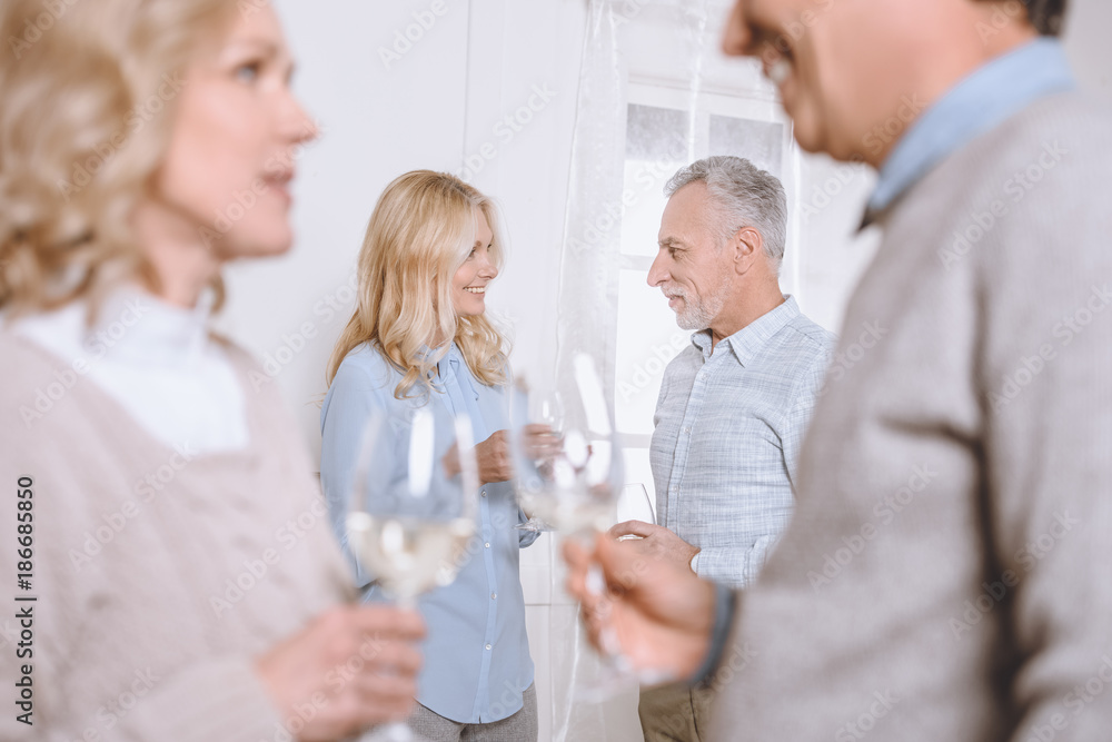 happy friends speaking and holding glasses in hands in room happy friends speaking and holding glasses in hands in room