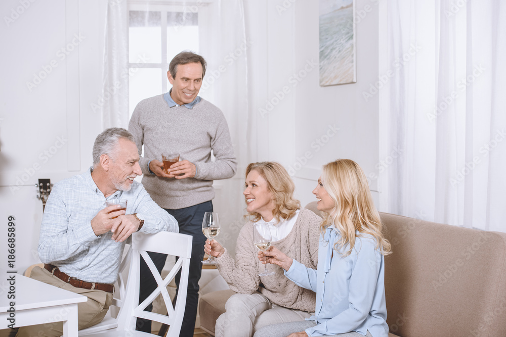 friends sitting on sofa and on chair while speaking in room friends sitting on sofa and on chair while speaking in room