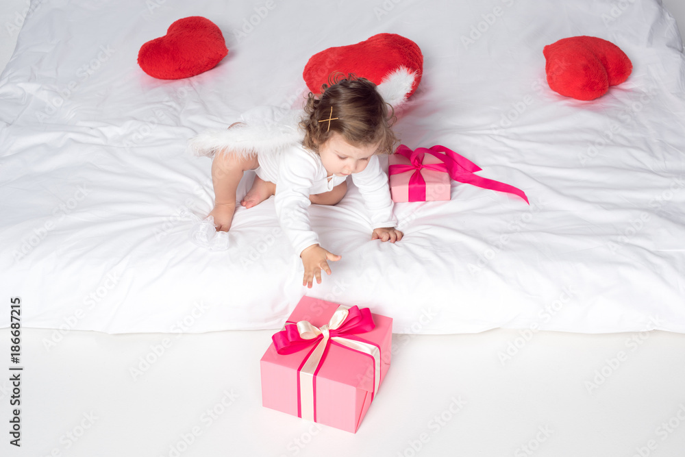 little cherub with wings on bed with hearts and presents little cherub with wings on bed with hearts and presents