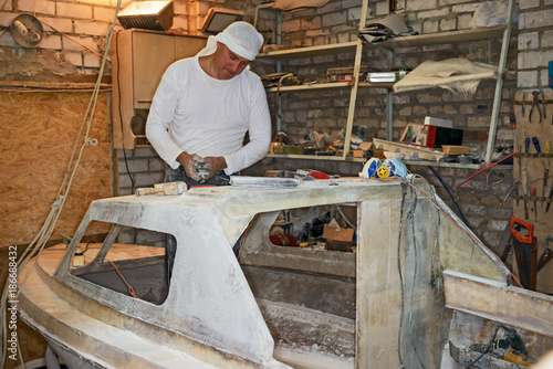 Man refits the motorboat in home workshop.