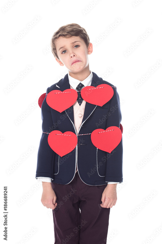 upset little boy in suit staying tied with rope and red hearts, looking at camera isolated on white upset little boy in suit staying tied with rope and red hearts, looking at camera isolated on white