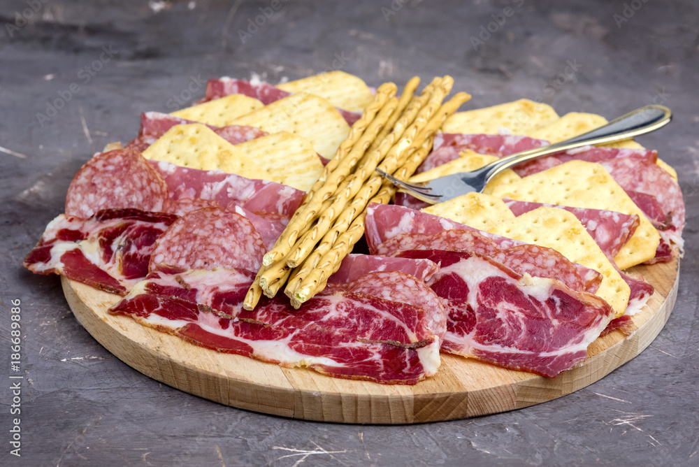 Food Tray With Delicious Salami Pieces of Sliced Ham and Crackers and Bread Sticks Meat Plate Food Tray With Delicious Salami Pieces of Sliced Ham and Crackers and Bread Sticks Meat Plate
