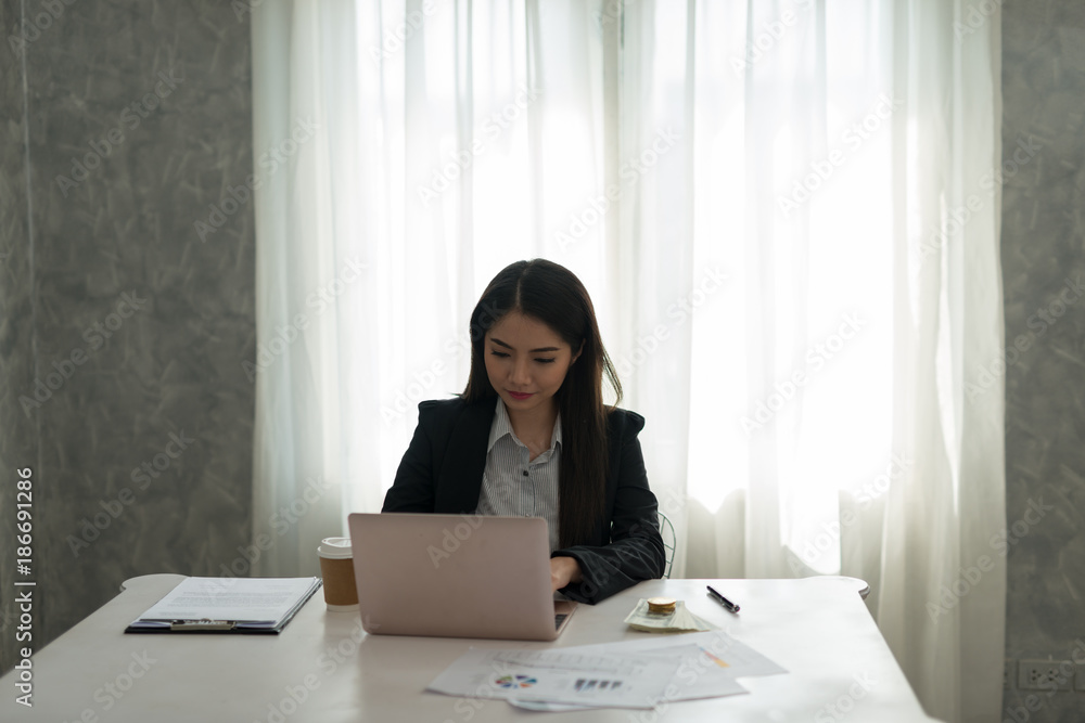 Beautiful asian young businesswoman working on laptop in her workstation. Beautiful asian young businesswoman working on laptop in her workstation.