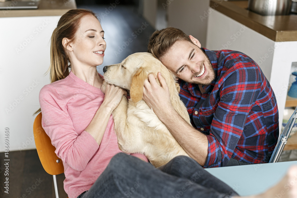 Happy young couple cuddling with dog at home Happy young couple cuddling with dog at home