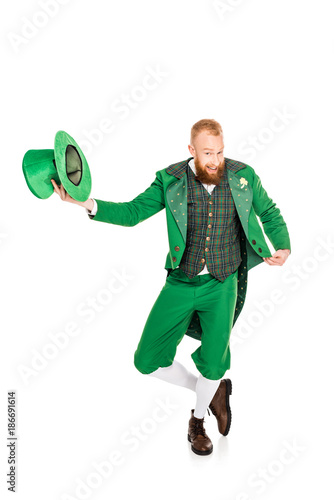 Fotografering handsome leprechaun in green costume holding hat, isolated on white