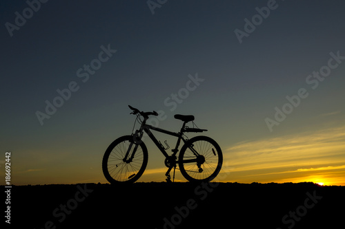Silhouette bicycle on the hill at sunset.