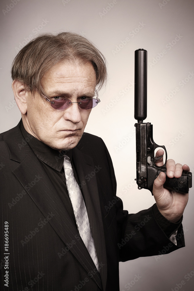 Ugly gunman armed with pistol with silencer in style of mob criminal Ugly gunman armed with pistol with silencer in style of mob criminal