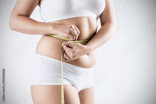 Overweight woman measuring her fat belly.