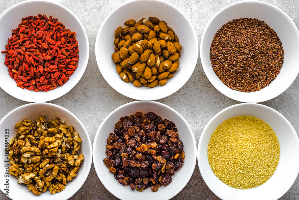 Vegetarian breakfast with healthy food selection, nuts, seeds, goji berries and other superfoods on table, flat lay, overhead Vegetarian breakfast with healthy food selection, nuts, seeds, goji berries and other superfoods on table, flat lay, overhead