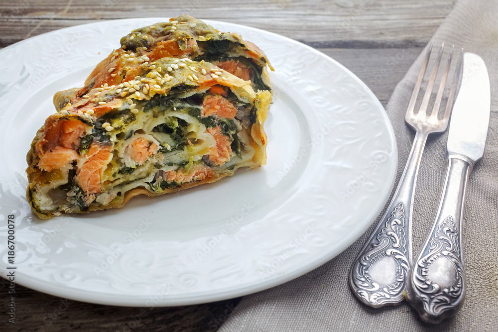 Strudel pie with salmon and spinach, served on wood table Strudel pie with salmon and spinach, served on wood table