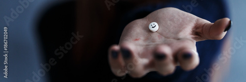 Teenager's hand with smiling pill photo