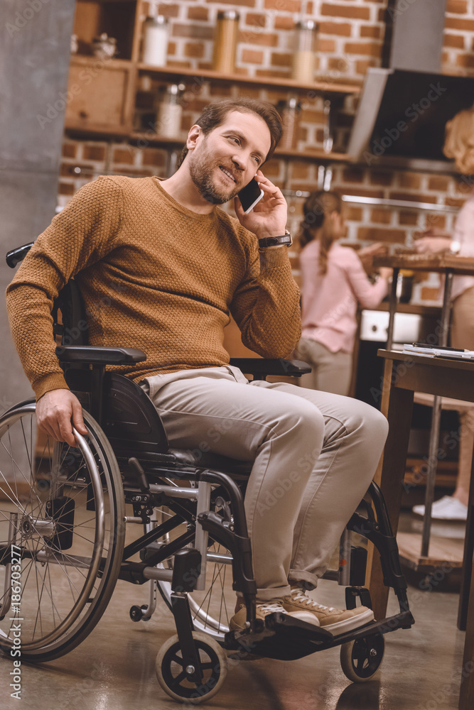 disabled man in wheelchair talking on smartphone at home disabled man in wheelchair talking on smartphone at home