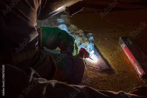 Welder perform welding to the metal plate at roof floor of manufacturing factory by using steel welding electrode in offshore oil and gas industrial operation, Blue collar jobs © eaumstocker