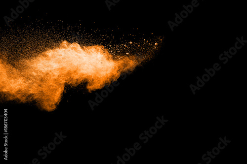 abstract orange powder explosion on black background. abstract orange dust splattered on black background. Freeze motion of orange powder splash.