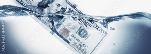 Slika na platnu Money concept showing US Dollar sinking in water as a symbol of global economic