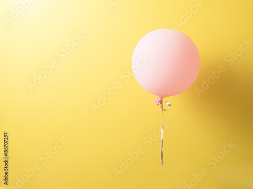 Pink balloon with shadows over yellow background