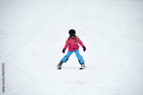 Child skiing in the mountains. Girl in colorful suit and safety helmet learning to ski. Winter sport for family with young children. Kids ski lesson in ski school.